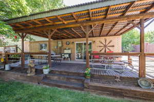 Expansive covered deck featuring a corrugated metal roof, exposed wood beams, wood decking, and direct access to the brick exterior