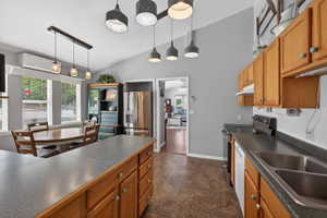 Open-concept kitchen with vaulted ceilings, featuring wood cabinetry, stainless steel appliances, and a double basin sink