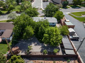 Property featuring a gravel lot, mature trees, a detached storage shed, a covered carport, and a brick privacy fence