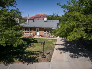 Brick exterior residence with a gray metal roof, featuring a white picket fence on the front porch