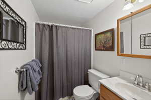 Bathroom featuring a white toilet, light wood-finish vanity with an integrated sink, and a framed mirror cabinet