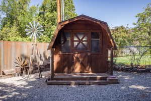 Barn-style shed featuring a wood door with X-detailing and a small front porch