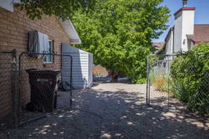 Gravel side yard featuring a chain-link fence, brick exterior, and a detached storage shed