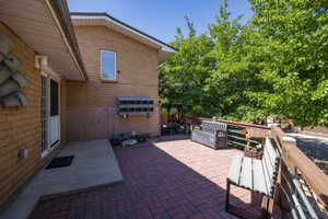 Brick exterior with a window and a white-framed sliding glass door opening onto a paver patio