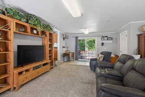 Spacious living area featuring neutral carpeting and a built-in entertainment center with open shelving