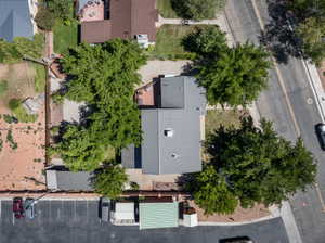 Property featuring a gray metal roof, mature trees, and a paved parking area