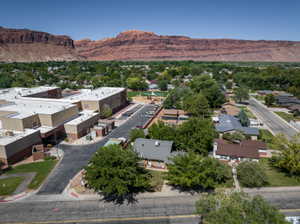 Expansive red rock geological formations provide a dramatic backdrop to the verdant landscape