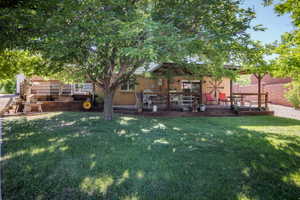 Expansive lawn area featuring a large mature tree, a multi-level wood deck, and a covered patio area