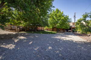 Gravel parking area featuring mature trees and a multi-level wood deck