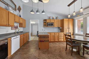 Vaulted ceiling kitchen featuring wood-finish cabinetry, a built-in microwave, and a double basin sink