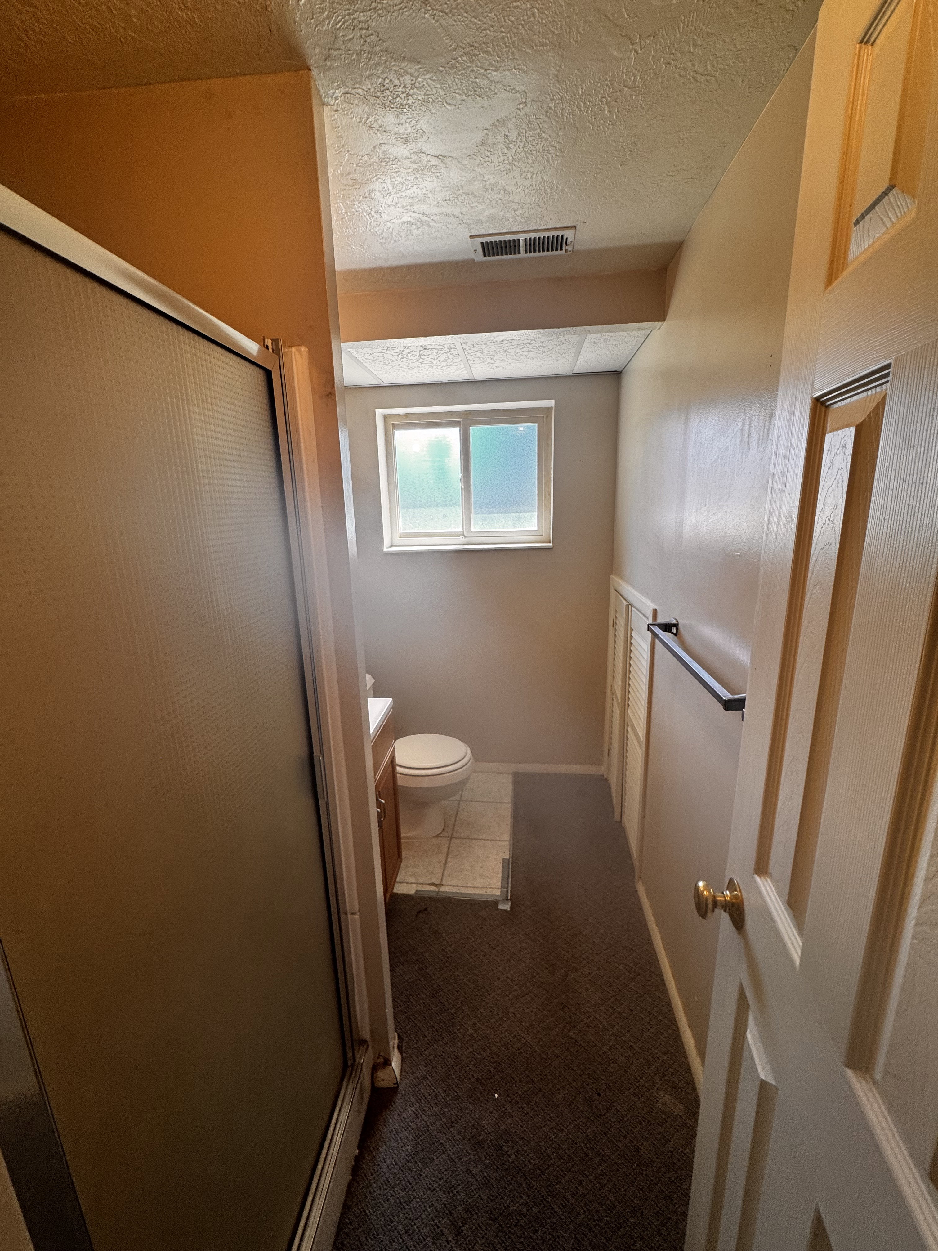 Bathroom featuring a glass-enclosed shower, a single window, a toilet, and a vanity with a surface-mounted sink