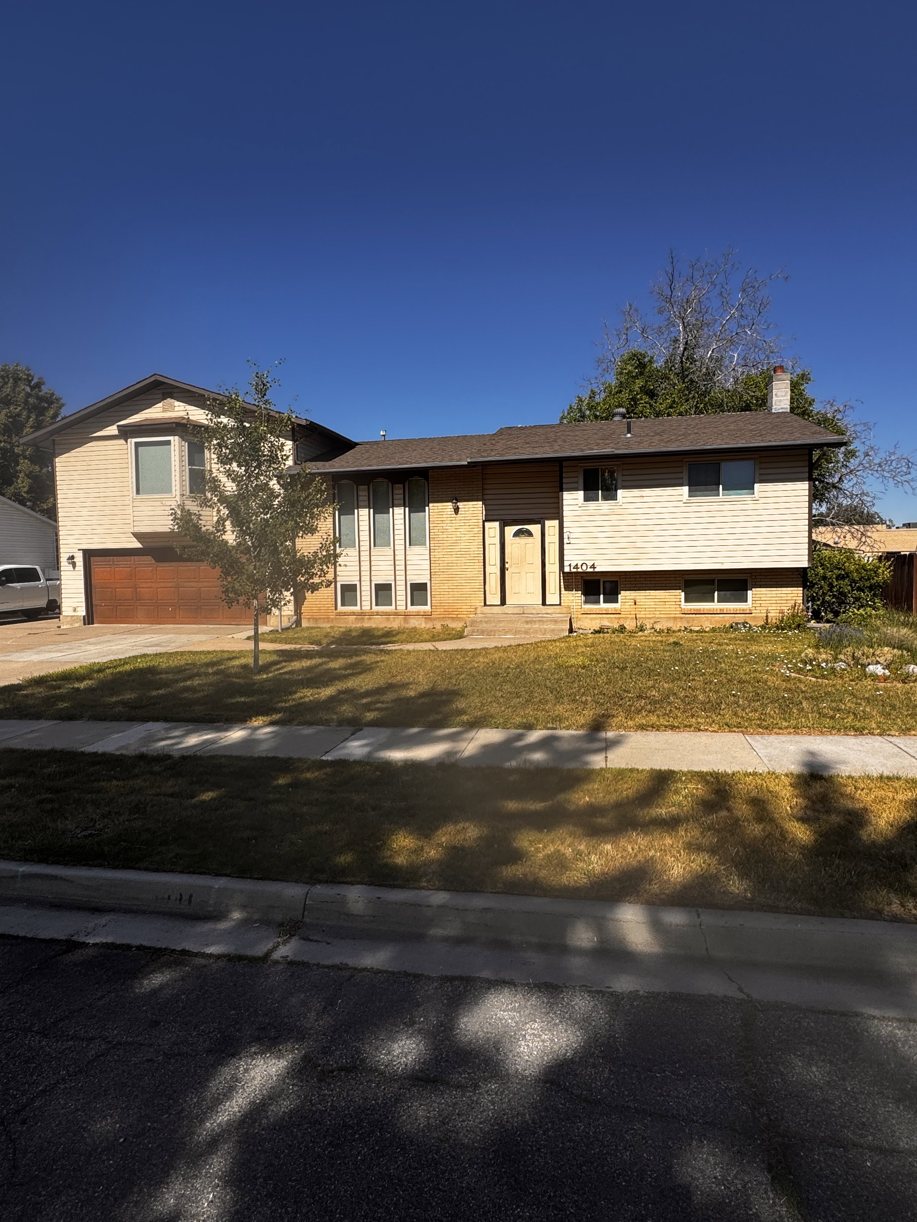 Split-level residence featuring a brown asphalt shingle roof and a two-car garage with a wood-finish door