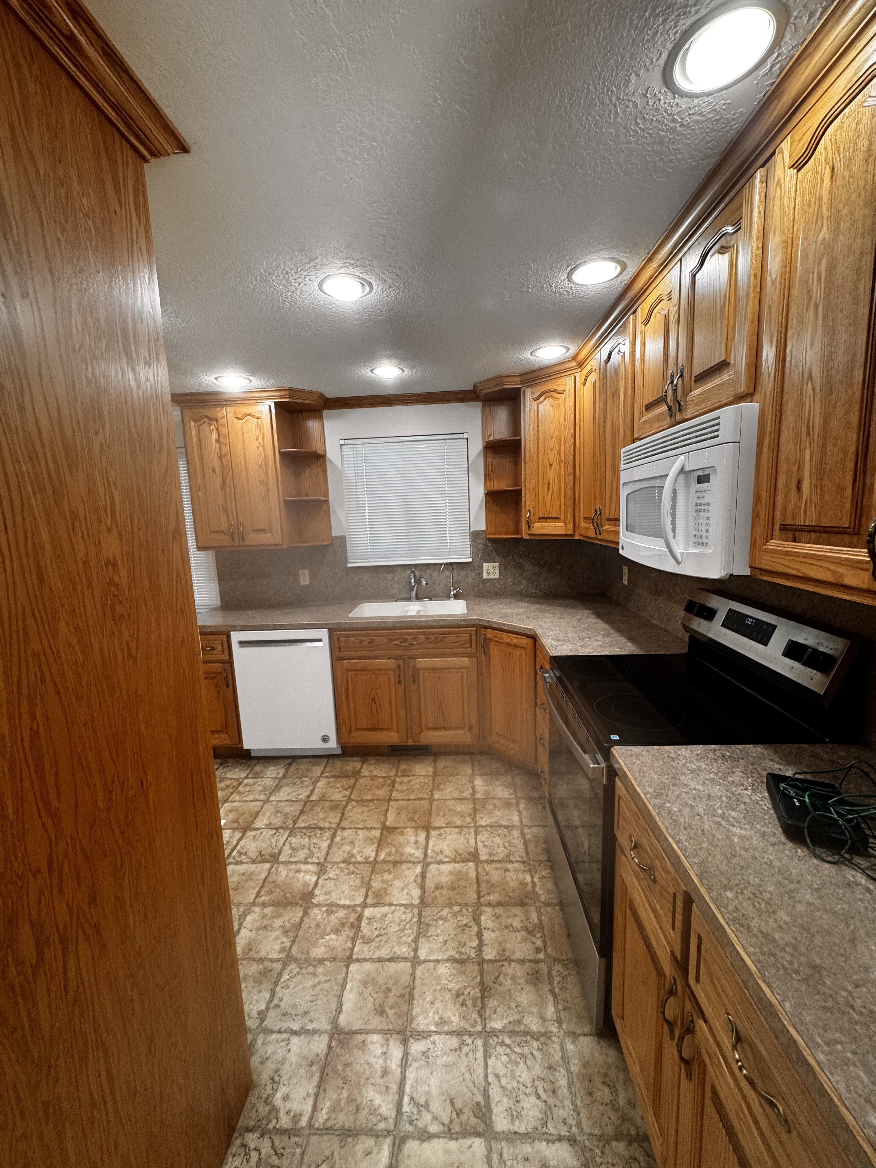 Well-appointed kitchen featuring wood-finish cabinetry, recessed lighting, and a white built-in microwave