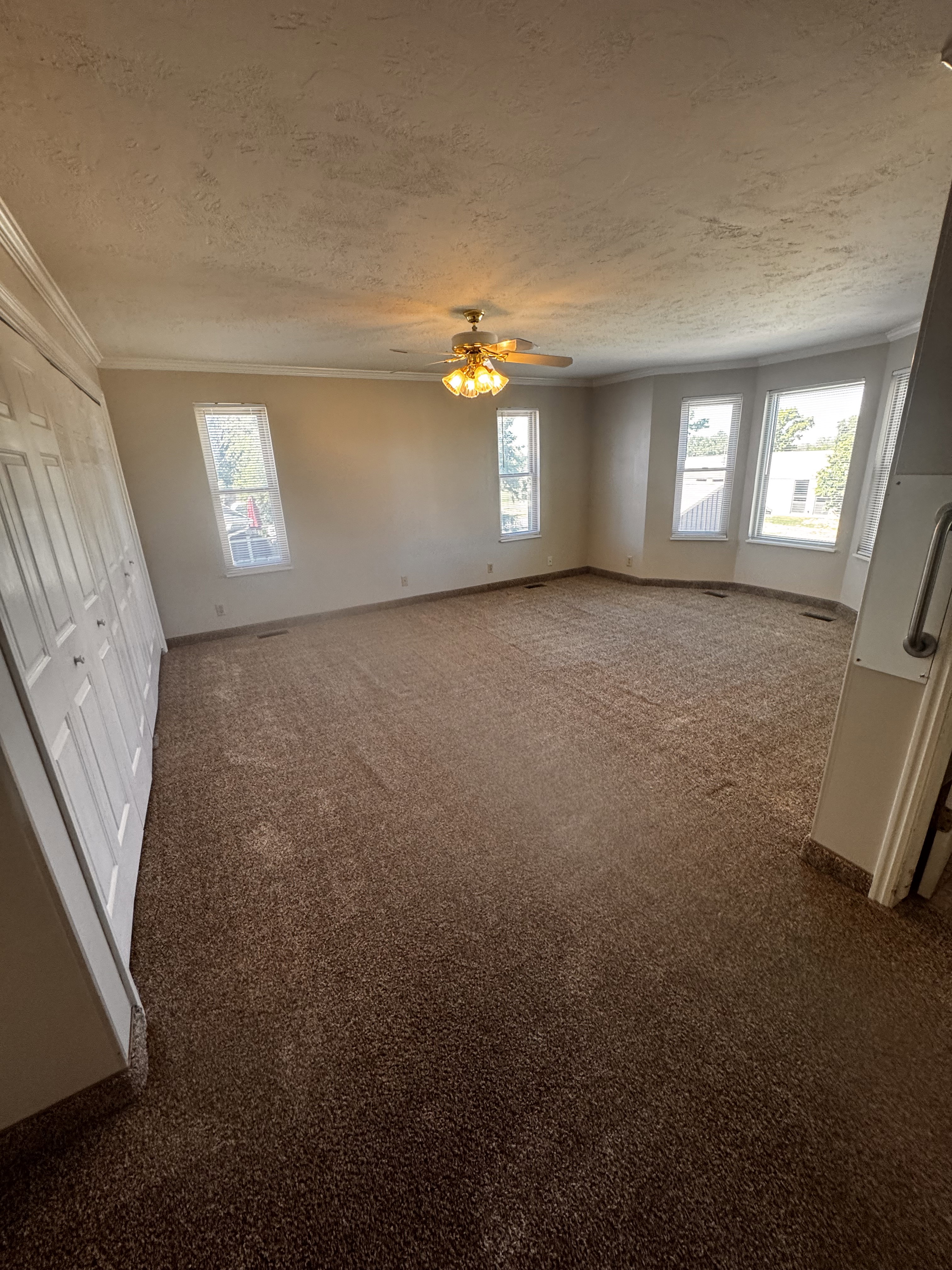 Spacious room featuring broadloom carpeting and a ceiling fan with integrated lighting