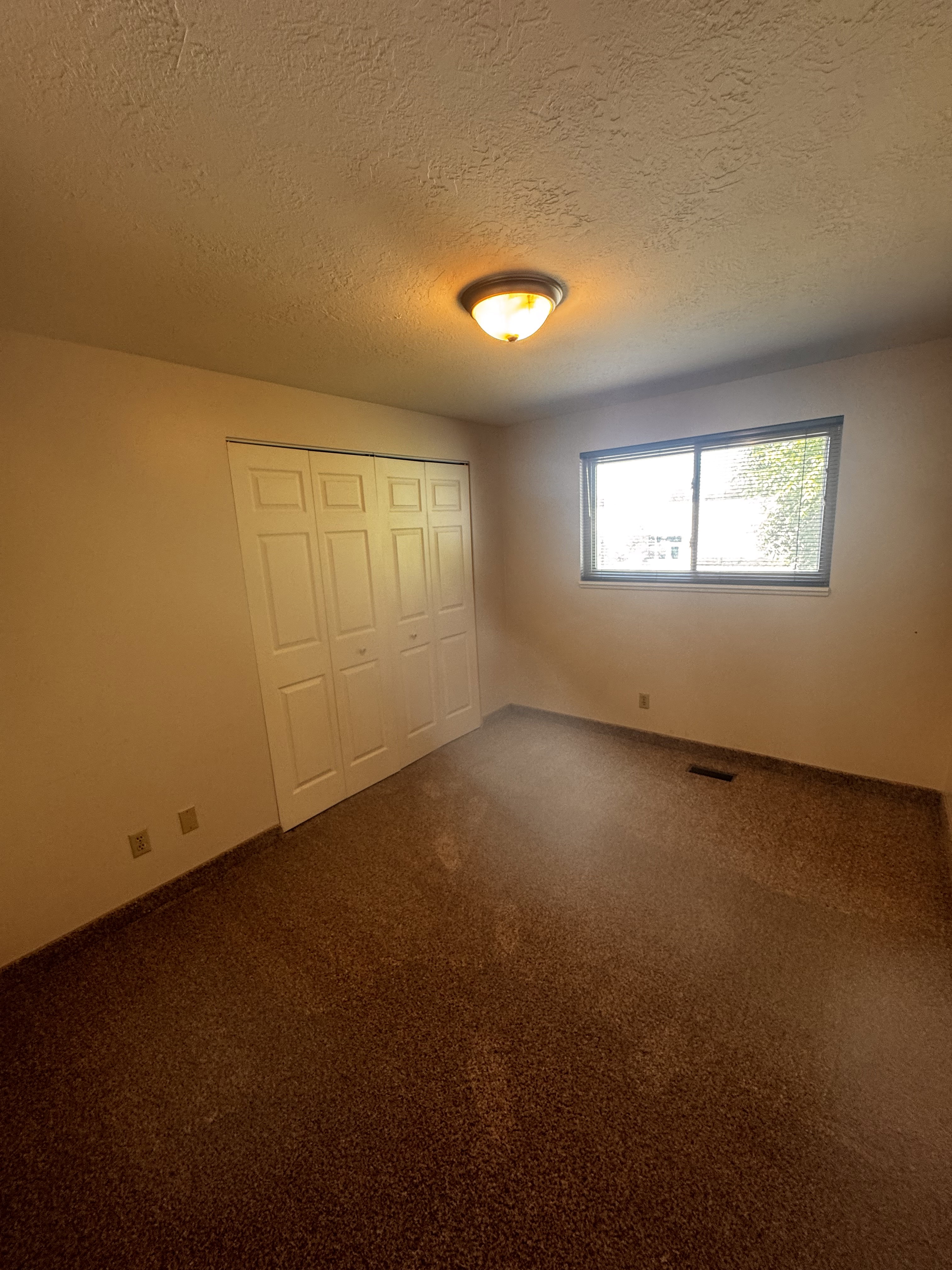 Bedroom featuring neutral-toned walls, recessed lighting, and a window providing natural illumination