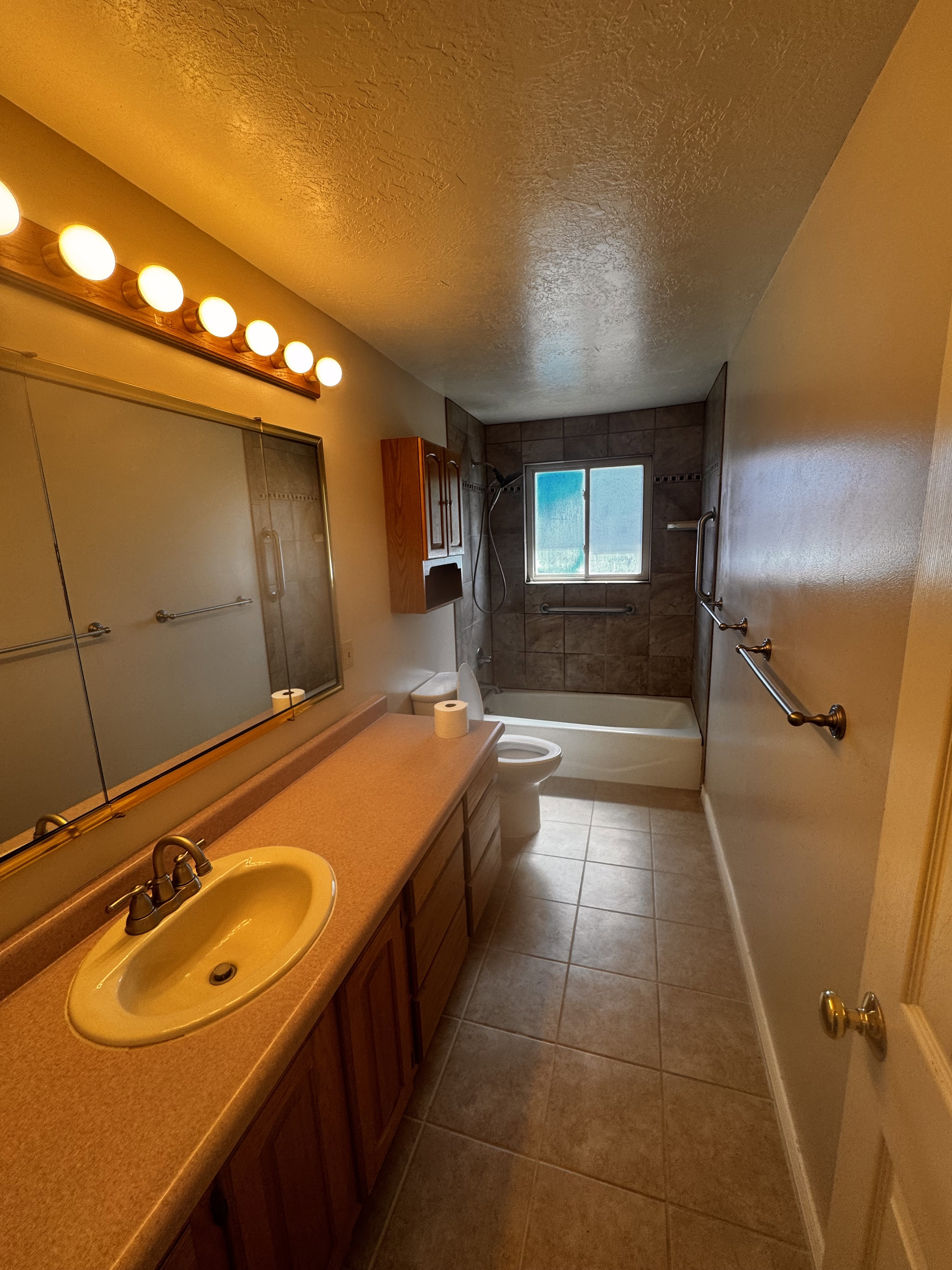 Full bathroom featuring a single vanity with an integrated sink and brushed nickel faucet, a large mirrored medicine cabinet, and wood-finish cabinetry