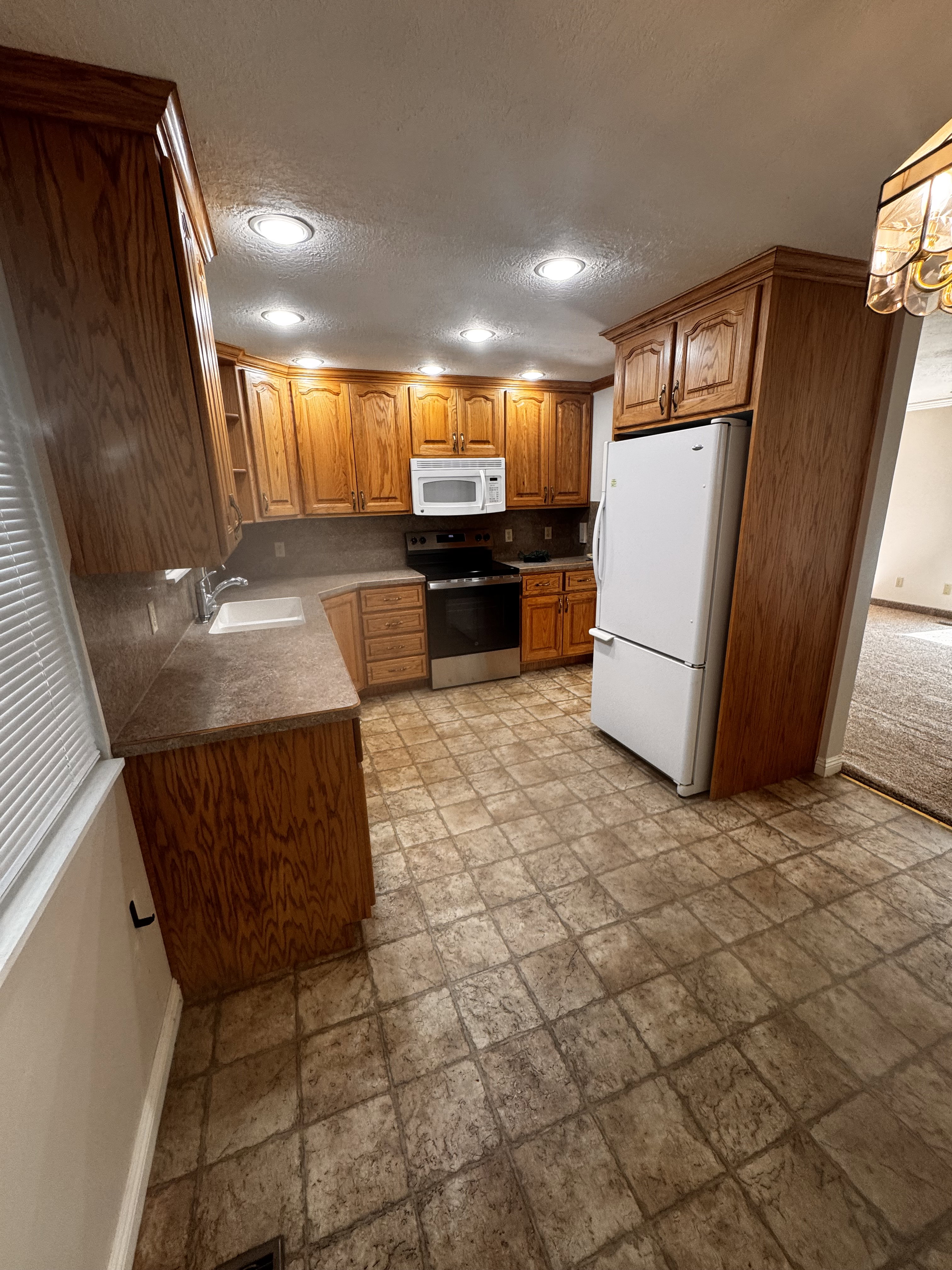 Kitchen featuring wood cabinetry, stone-look countertops, and recessed lighting