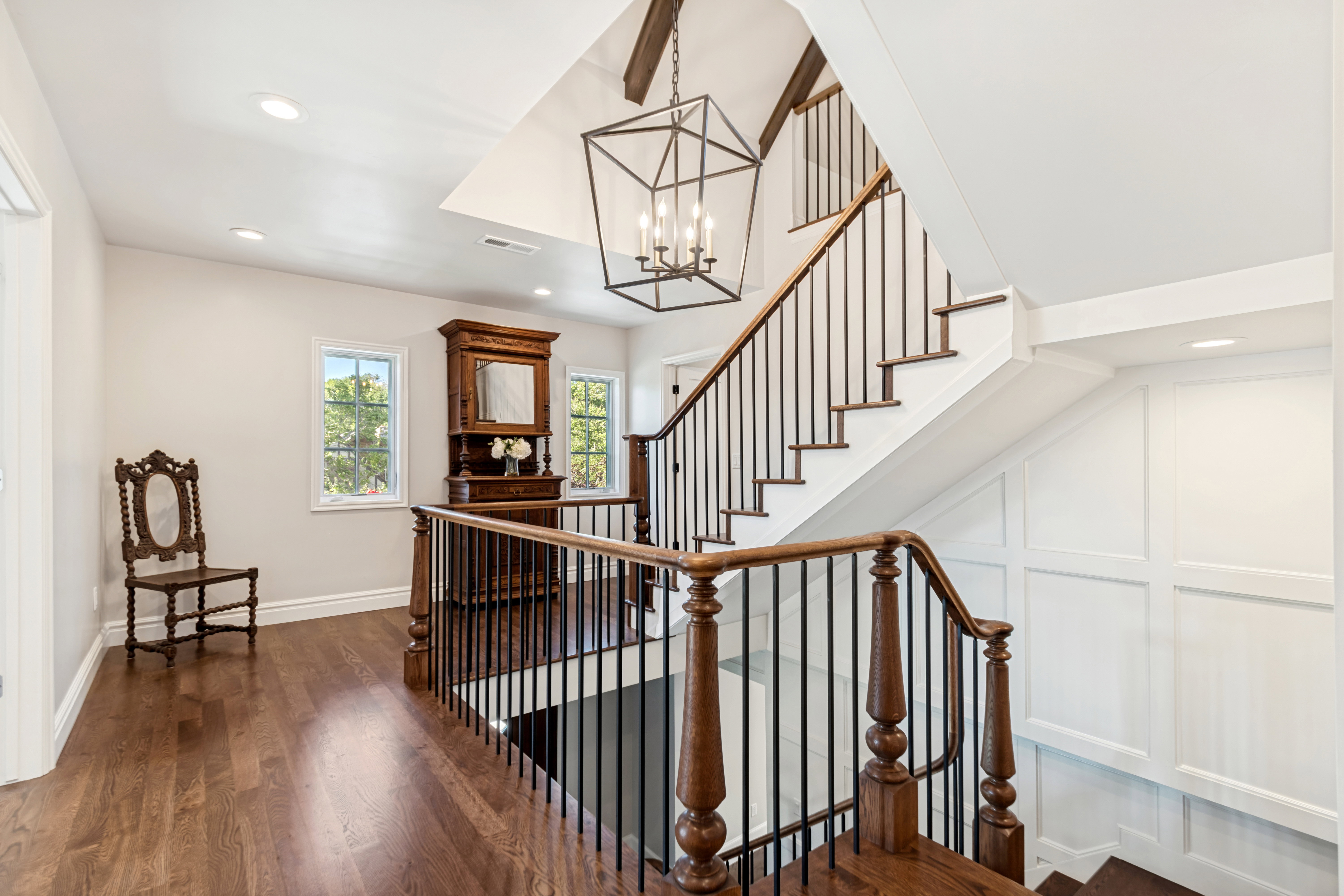 Staircase featuring dark wood handrails, black metal balusters, and white risers