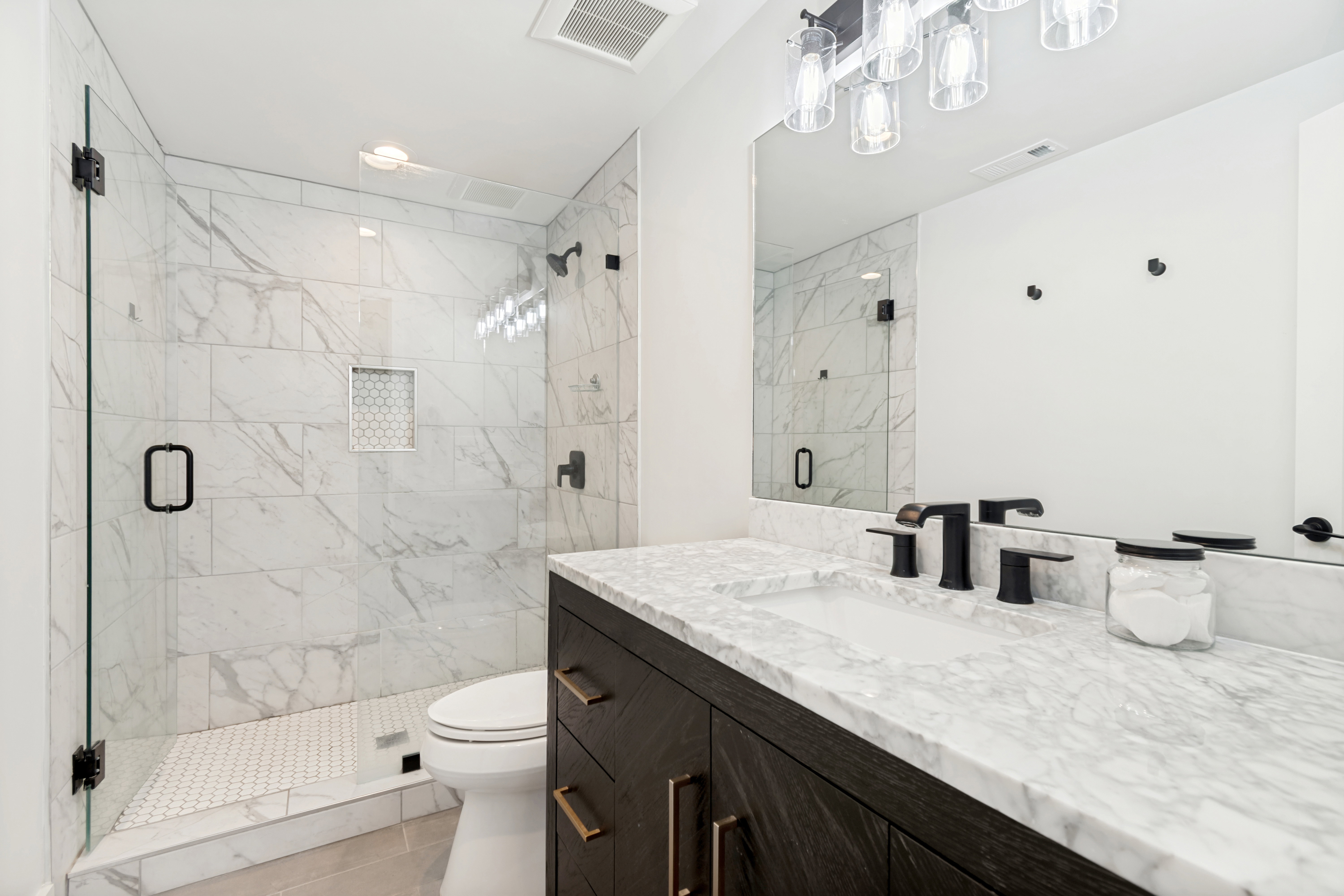 Modern bathroom featuring a dark wood-finish vanity with a white stone countertop, undermount sink, and matte black fixtures