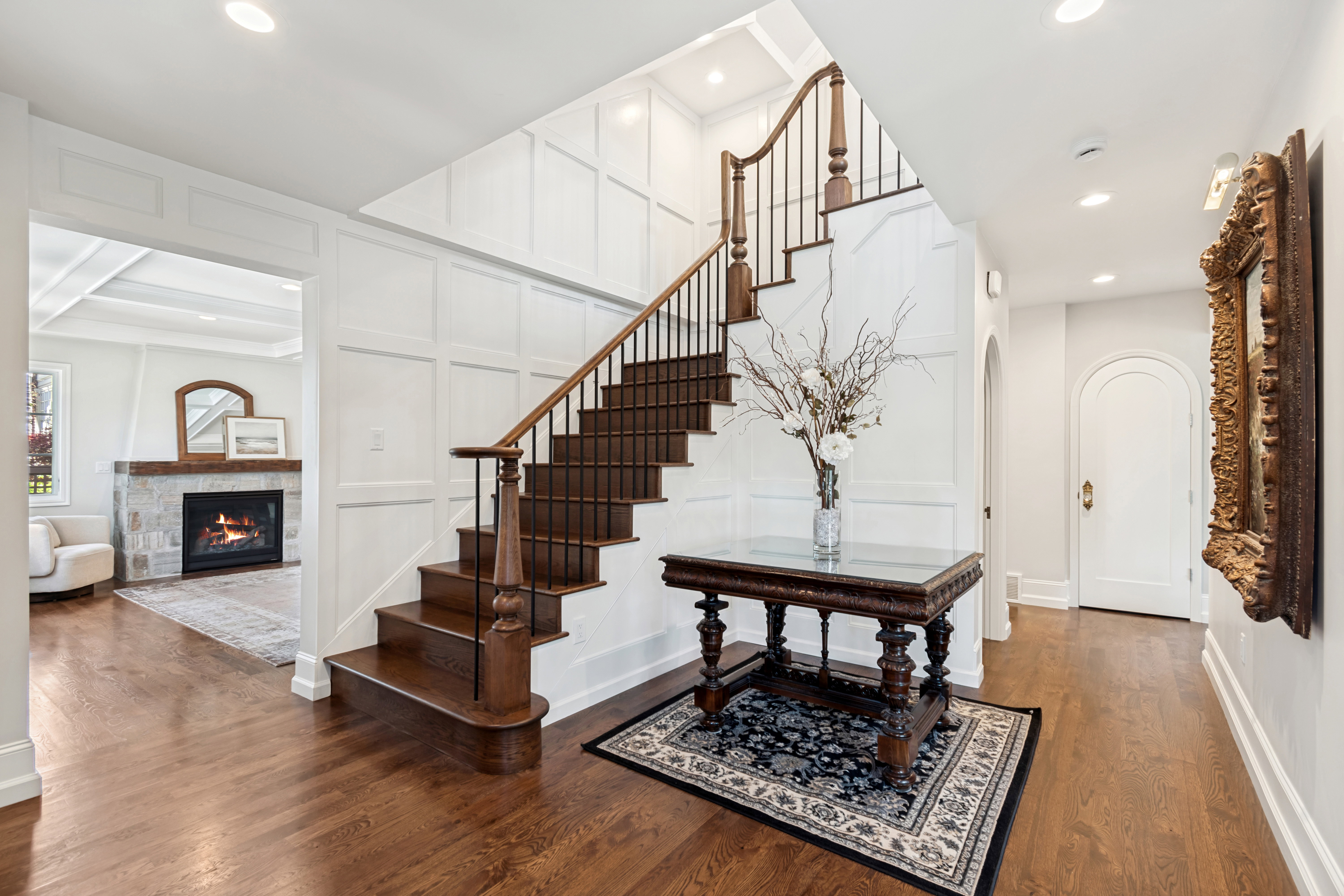 Two-story foyer featuring dark wood-finish flooring, white wainscoting, and a prominent staircase with dark wood treads and wrought iron balusters