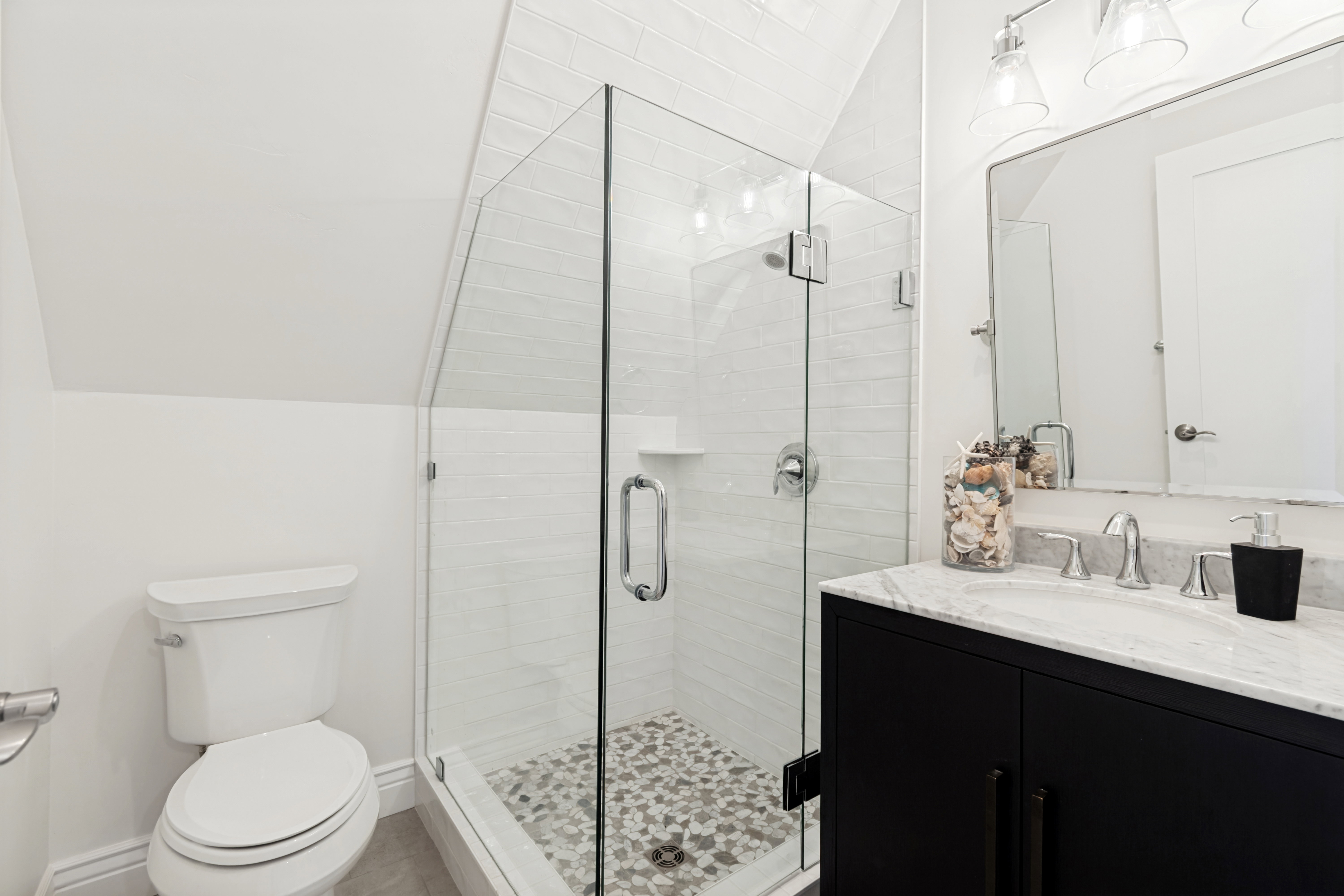 Glass-enclosed shower with pebble-tile flooring and white subway tile surround