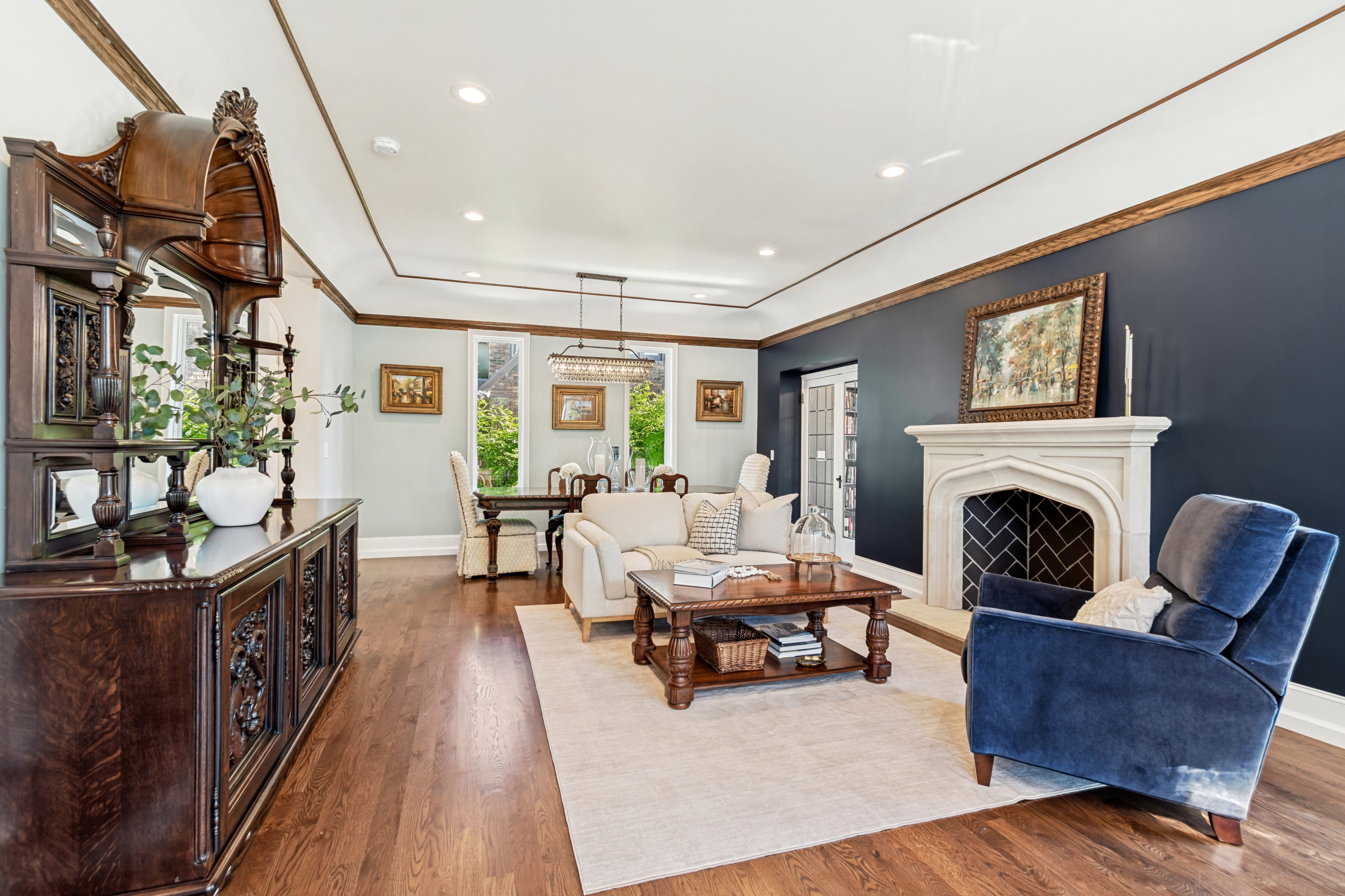 Spacious living area featuring rich hardwood flooring and a stone fireplace with a herringbone pattern firebox