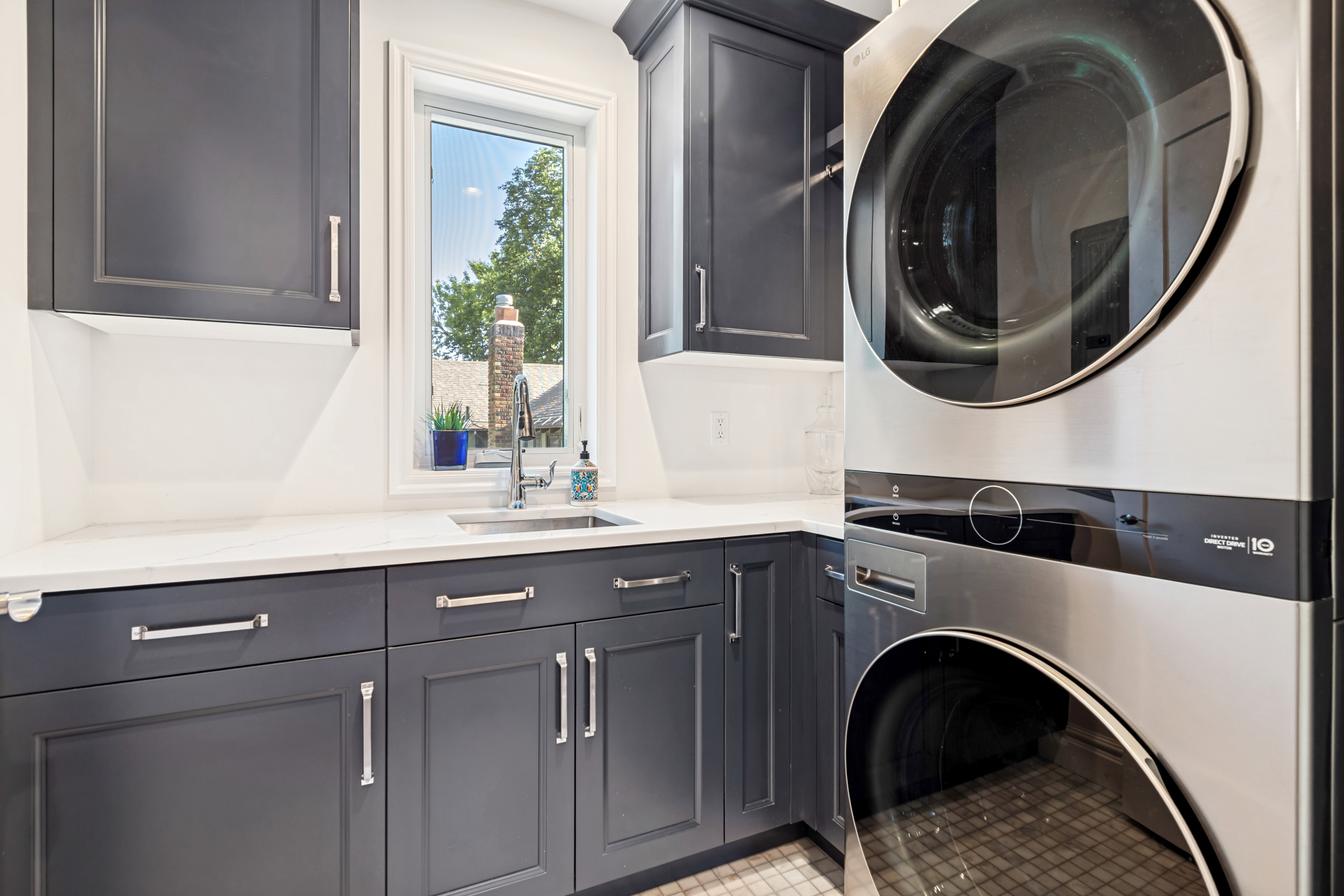 Laundry area featuring stacked stainless steel appliances