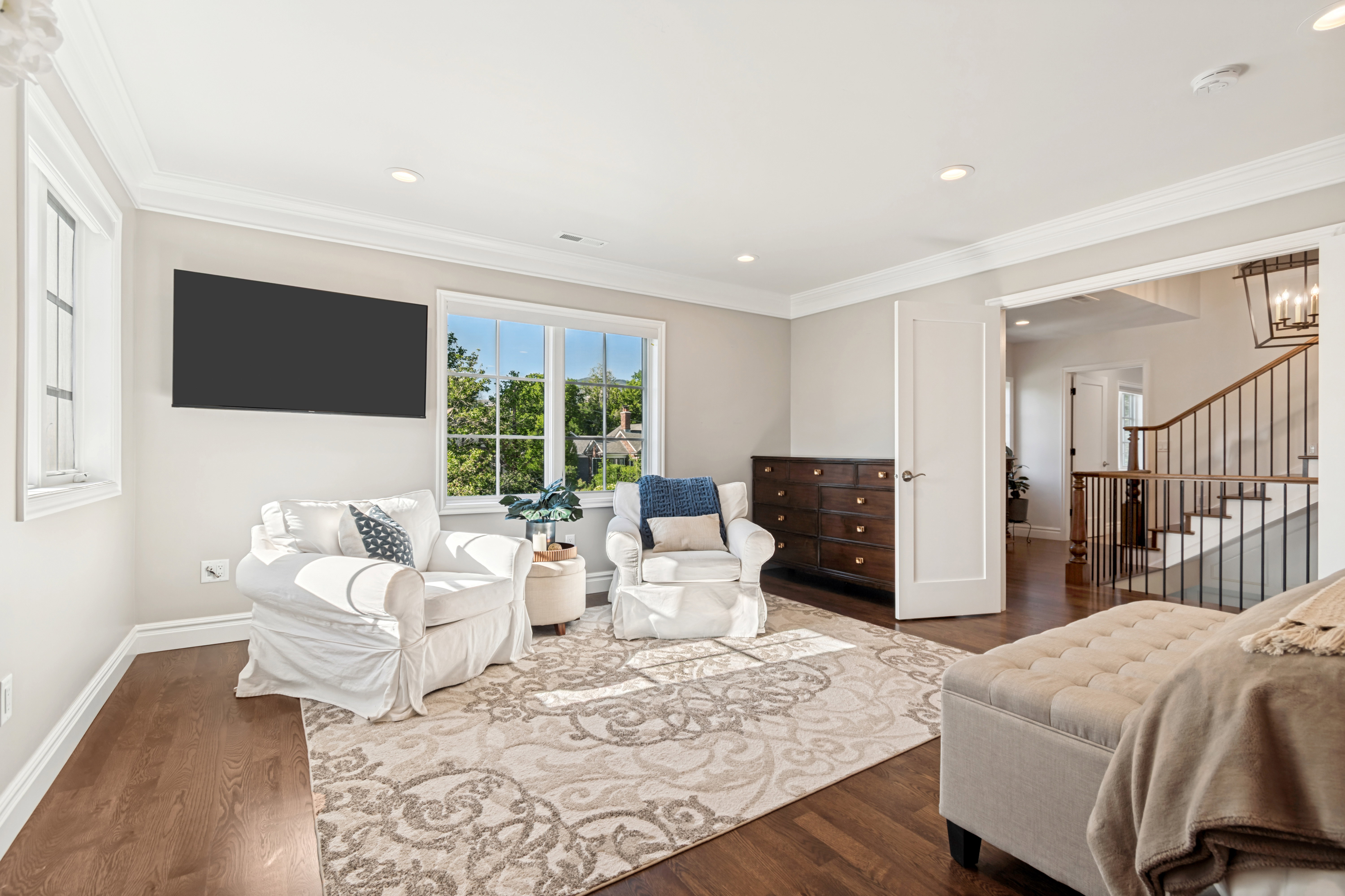 Spacious room featuring rich wood-finish flooring, recessed lighting, and crown molding