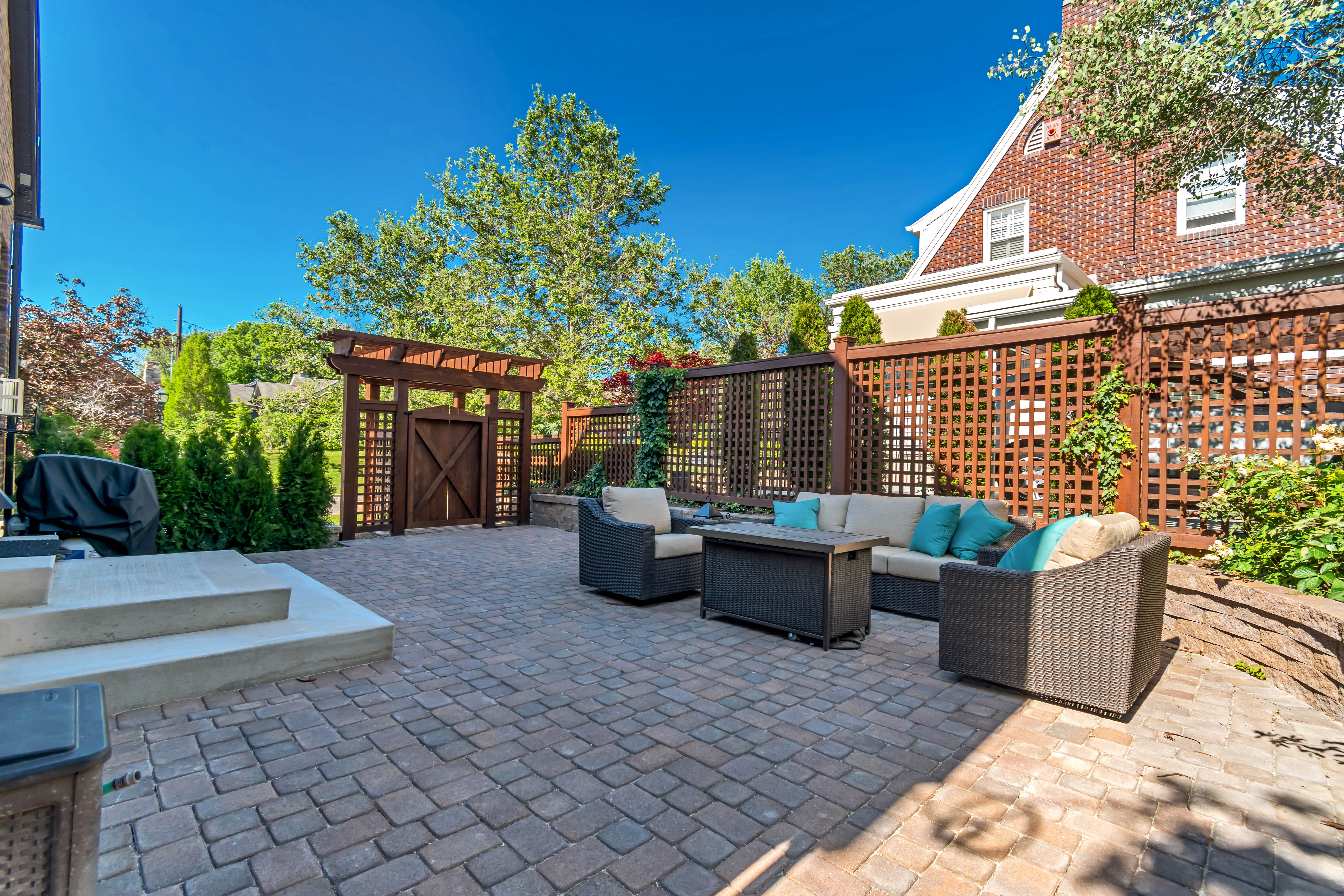 Paver patio with a decorative wooden gate and pergola