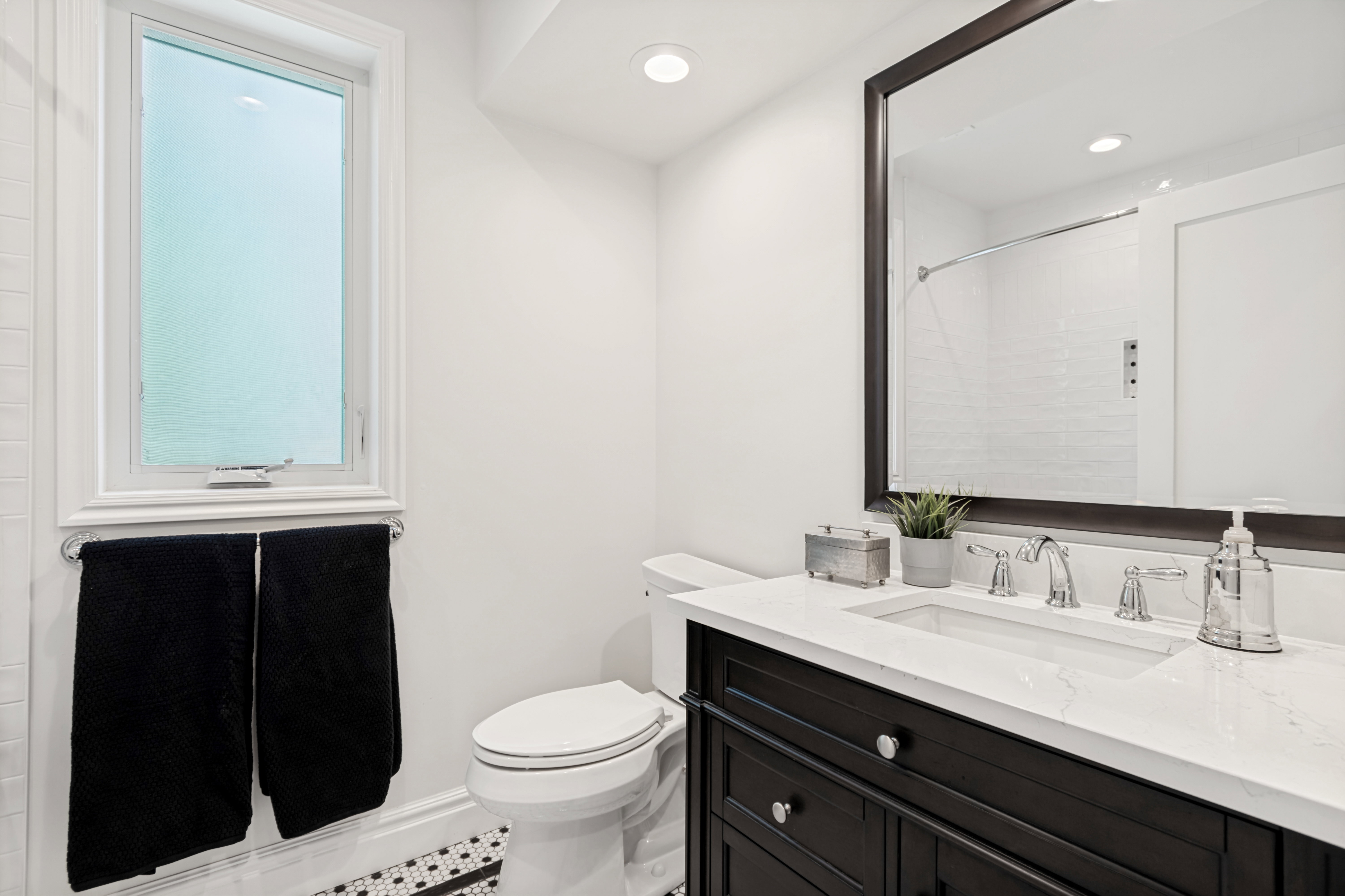 Bathroom featuring a dark wood vanity with a white countertop, undermount sink, and polished chrome fixtures