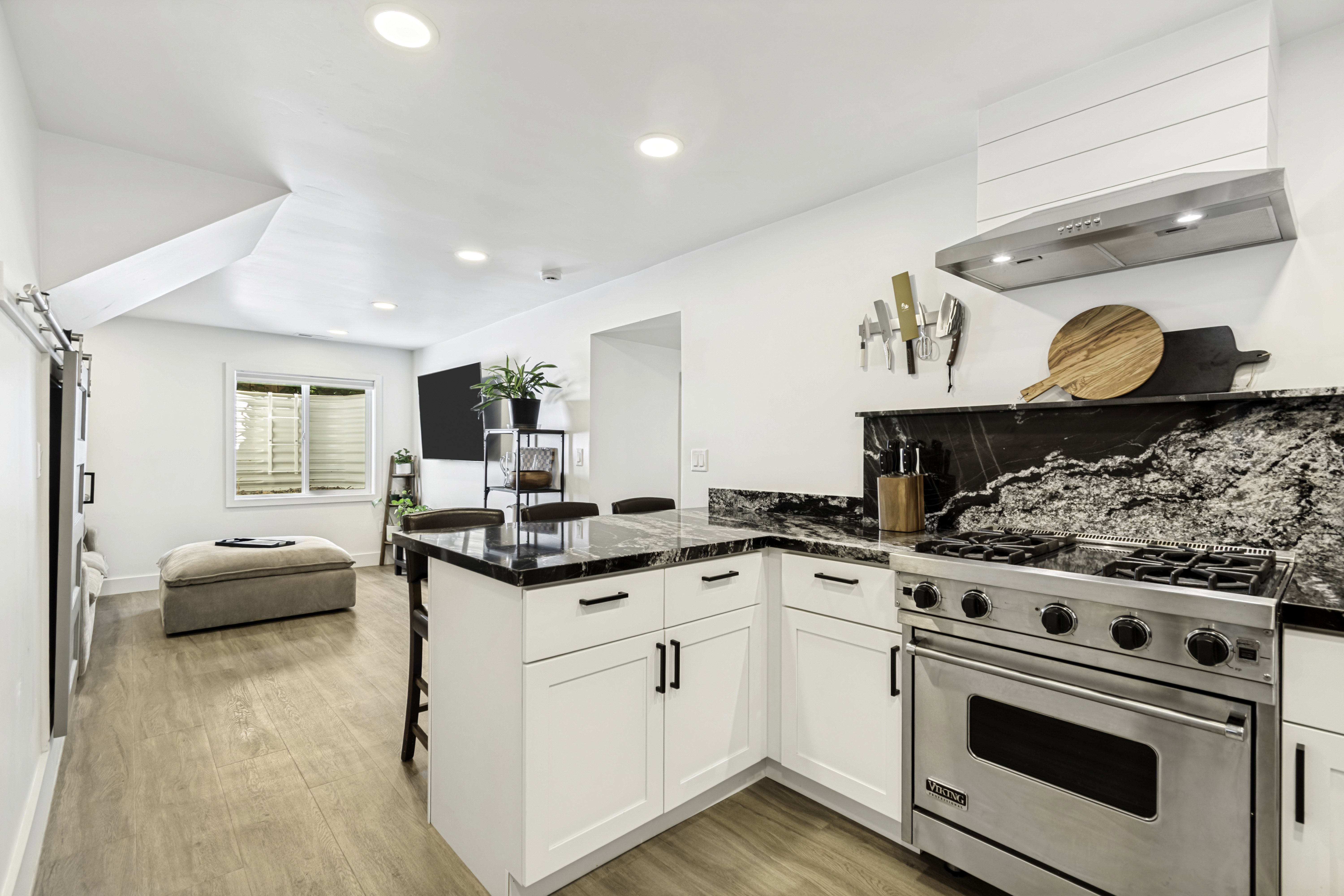 White shaker cabinetry with dark hardware, a professional-grade stainless steel range, and a custom range hood with shiplap detail