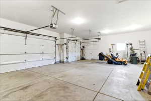 Spacious three-car garage featuring concrete flooring, multiple overhead garage door openers, and recessed lighting