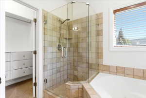 Walk-in shower with clear glass enclosure and square tile surround