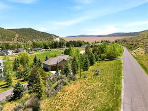 Expansive property featuring a paved road, scattered trees, and a distant mountain backdrop