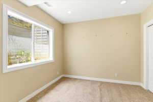 Recessed lighting illuminates this room, featuring light-toned carpeting and a white trim package