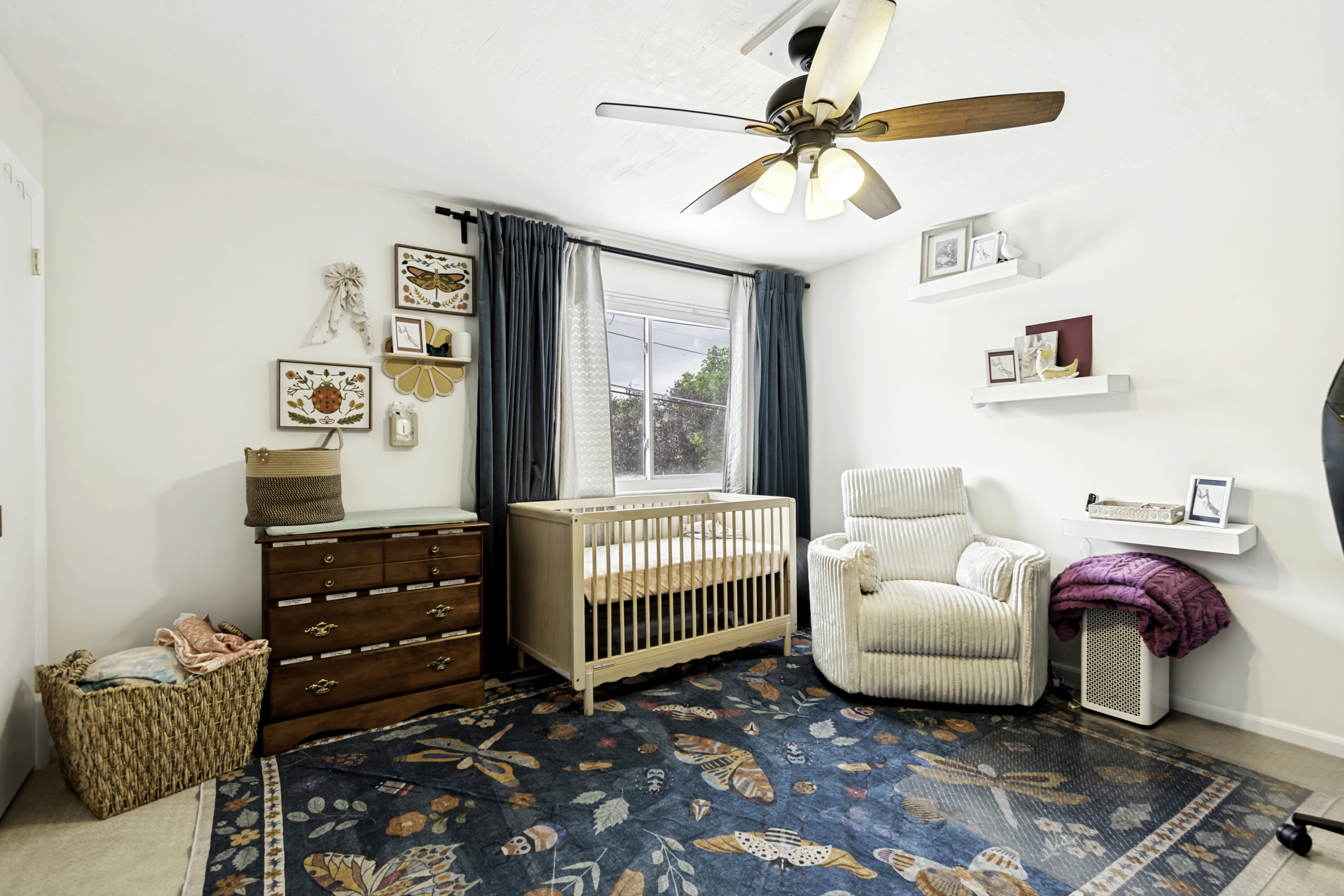 Windowed room featuring a ceiling fan with integrated lighting, wall-mounted shelving, and light-toned wall paint