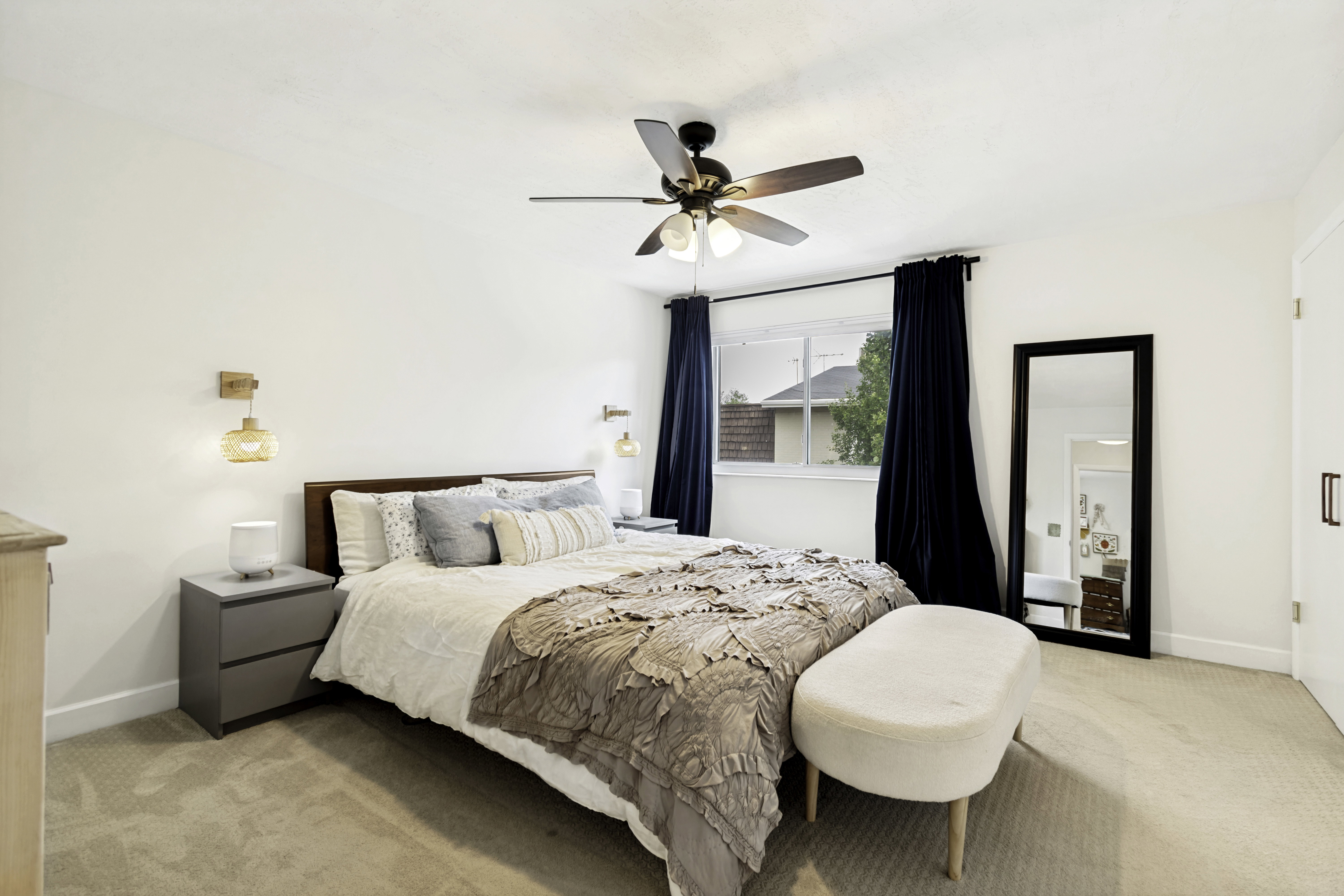 Neutral wall paint and carpeted flooring define this room, featuring a window with dark drapery