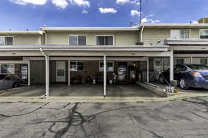 Townhome exterior featuring individual carports, upper-level windows, and a brick facade on the lower level