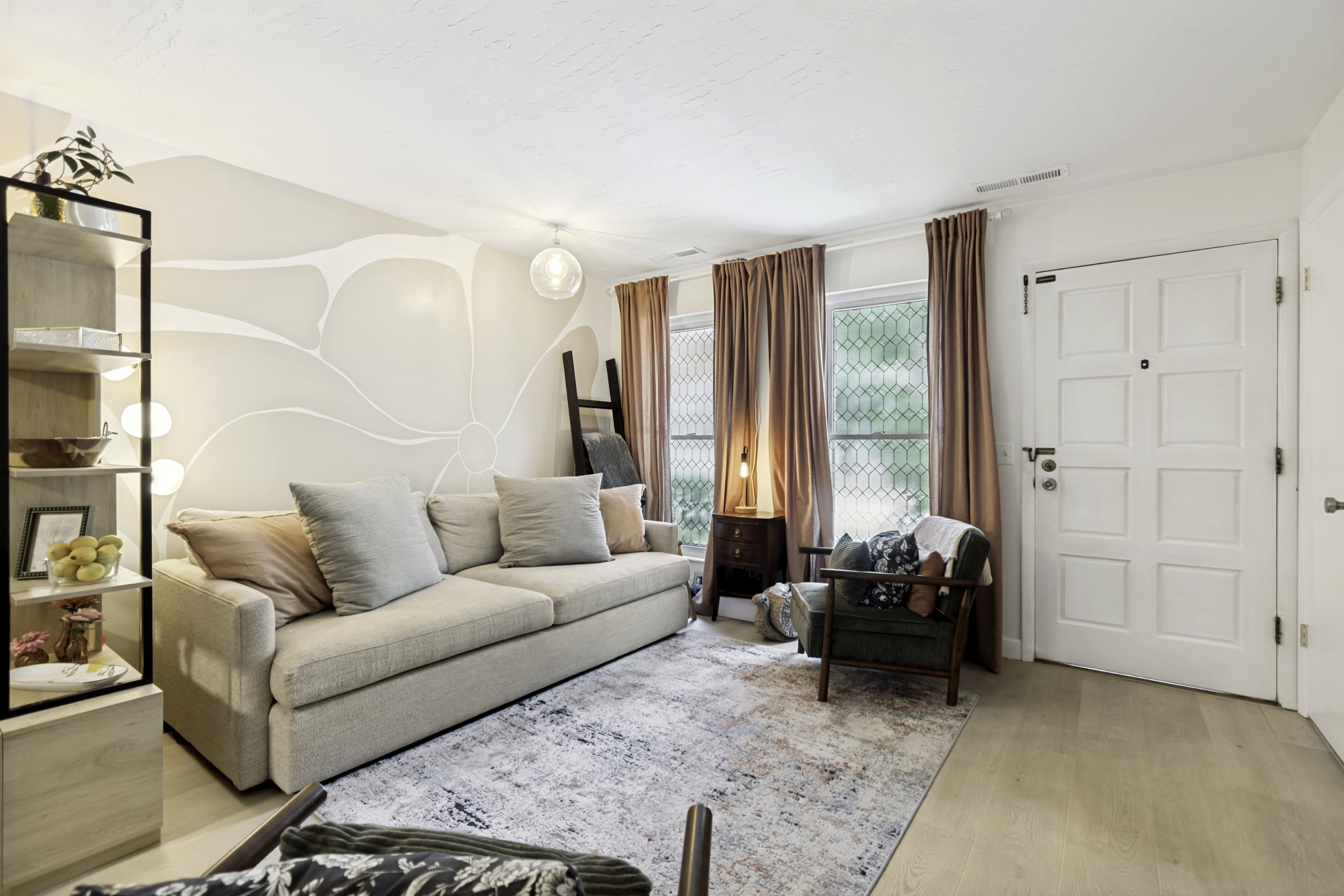 Living area featuring light wood-finish flooring, a decorative wall mural, and a paneled entry door