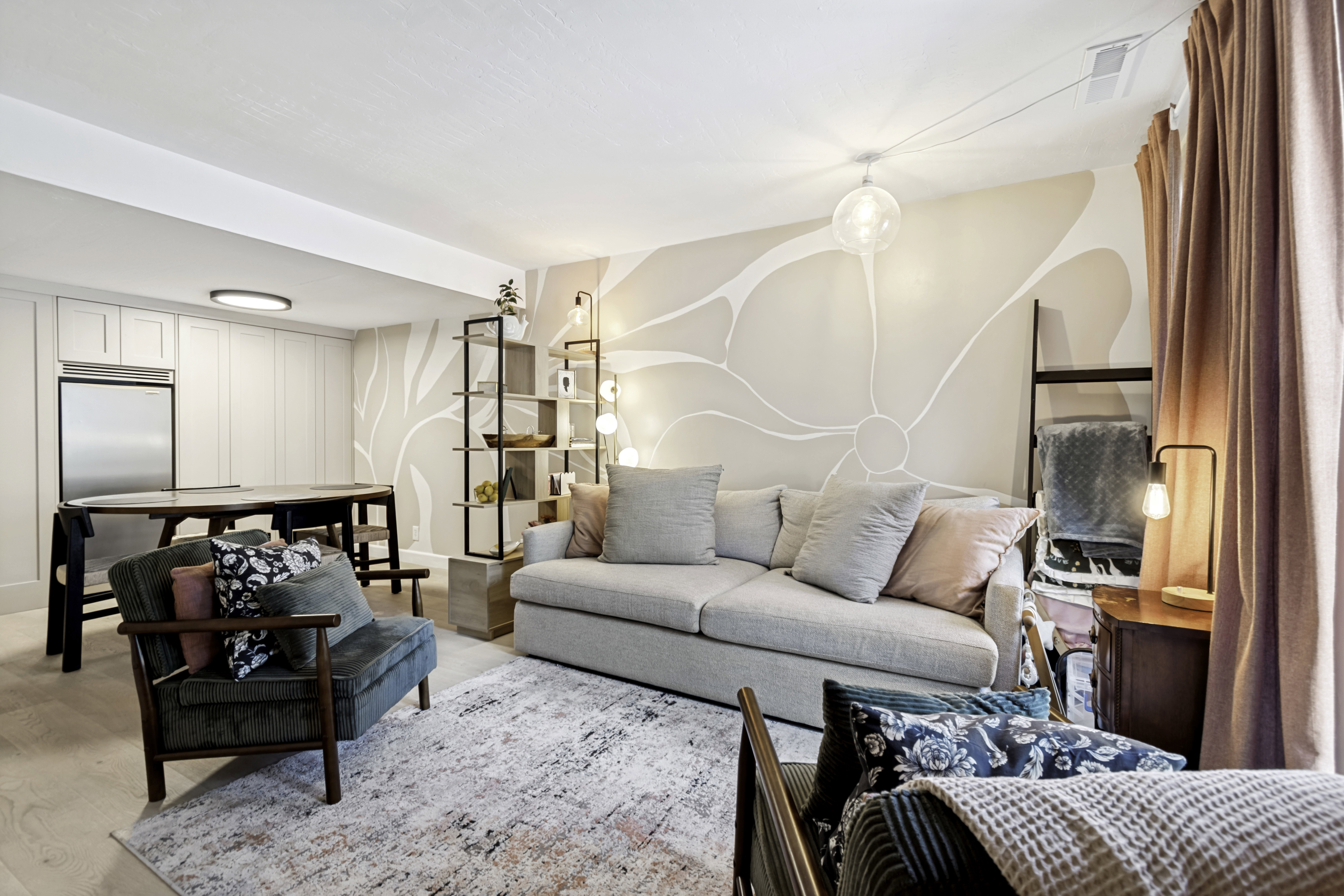 Living area featuring light wood-finish flooring, a decorative accent wall, and recessed and pendant lighting