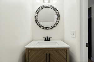 Modern vanity featuring a patterned wood-finish cabinet with black hardware, a light-toned countertop with integrated sink, and a matte black faucet