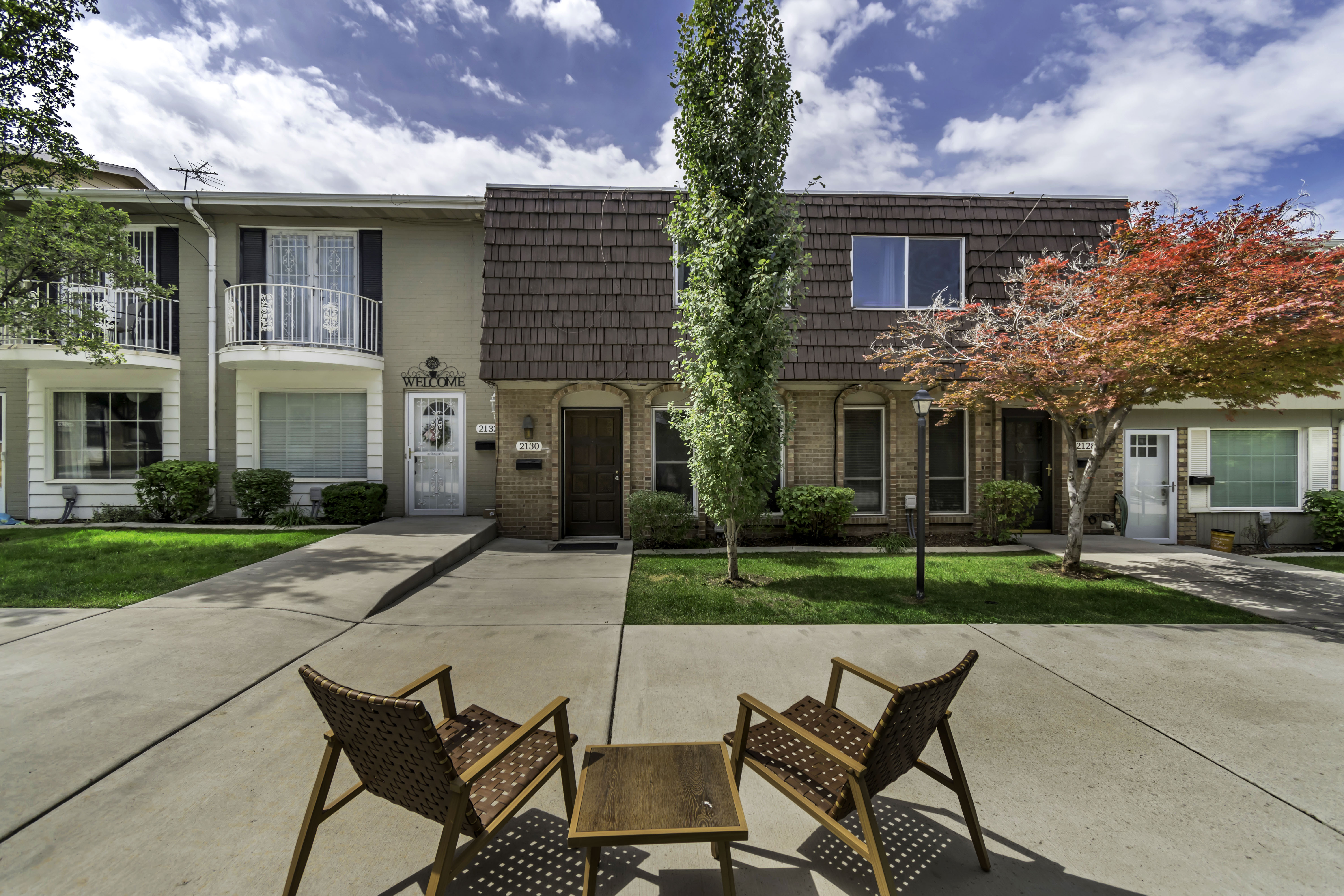 Townhome exterior featuring brick and siding facades, architectural shingles, mature landscaping, and an inviting front walkway
