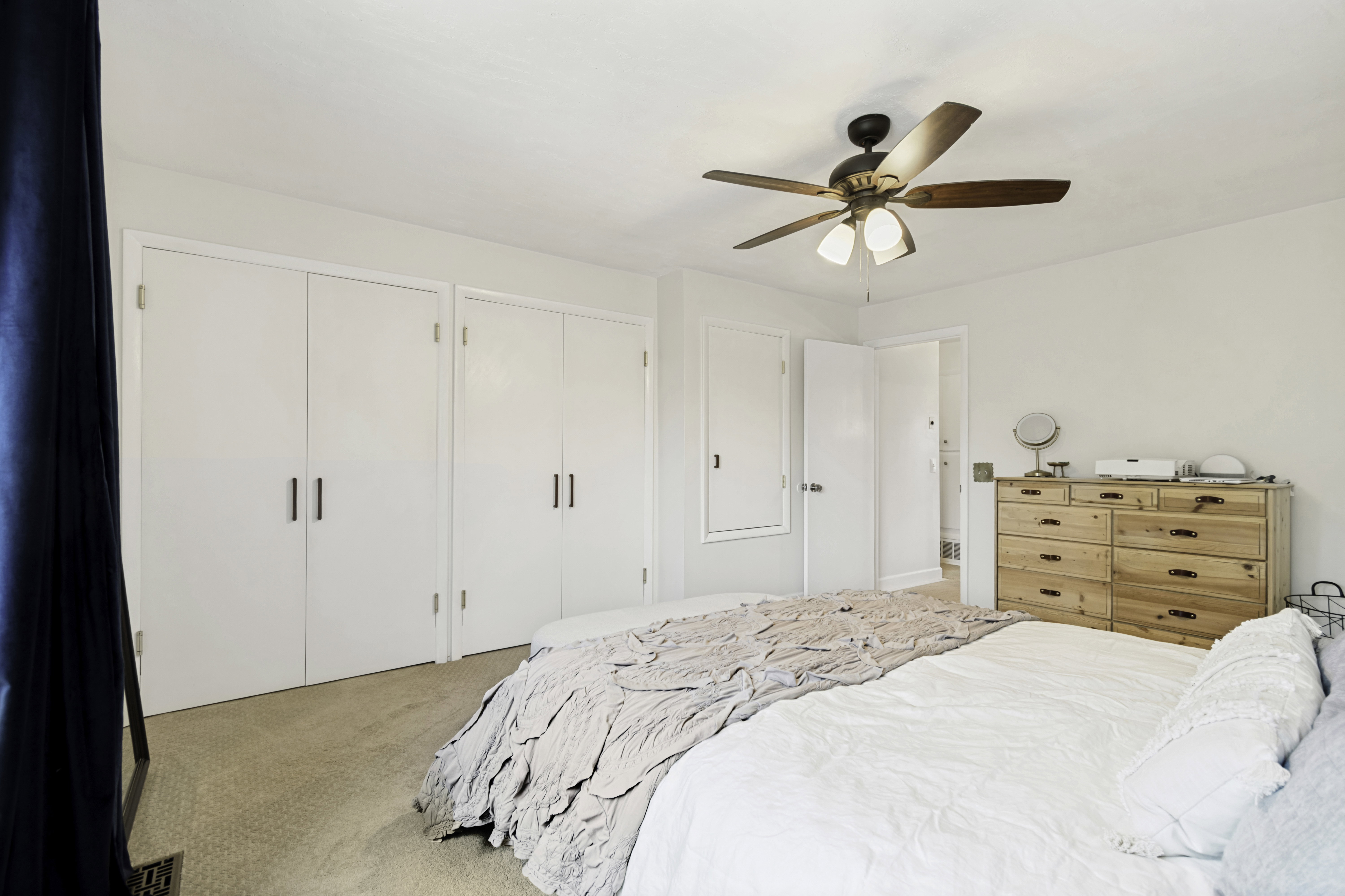Interior room featuring light-colored carpeting, a ceiling fan with light fixture, and white walls