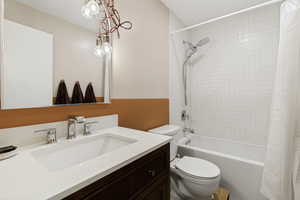Bathroom featuring a white integrated sink with chrome fixtures, a wood-finish vanity, and a mirror with an exposed bulb light fixture