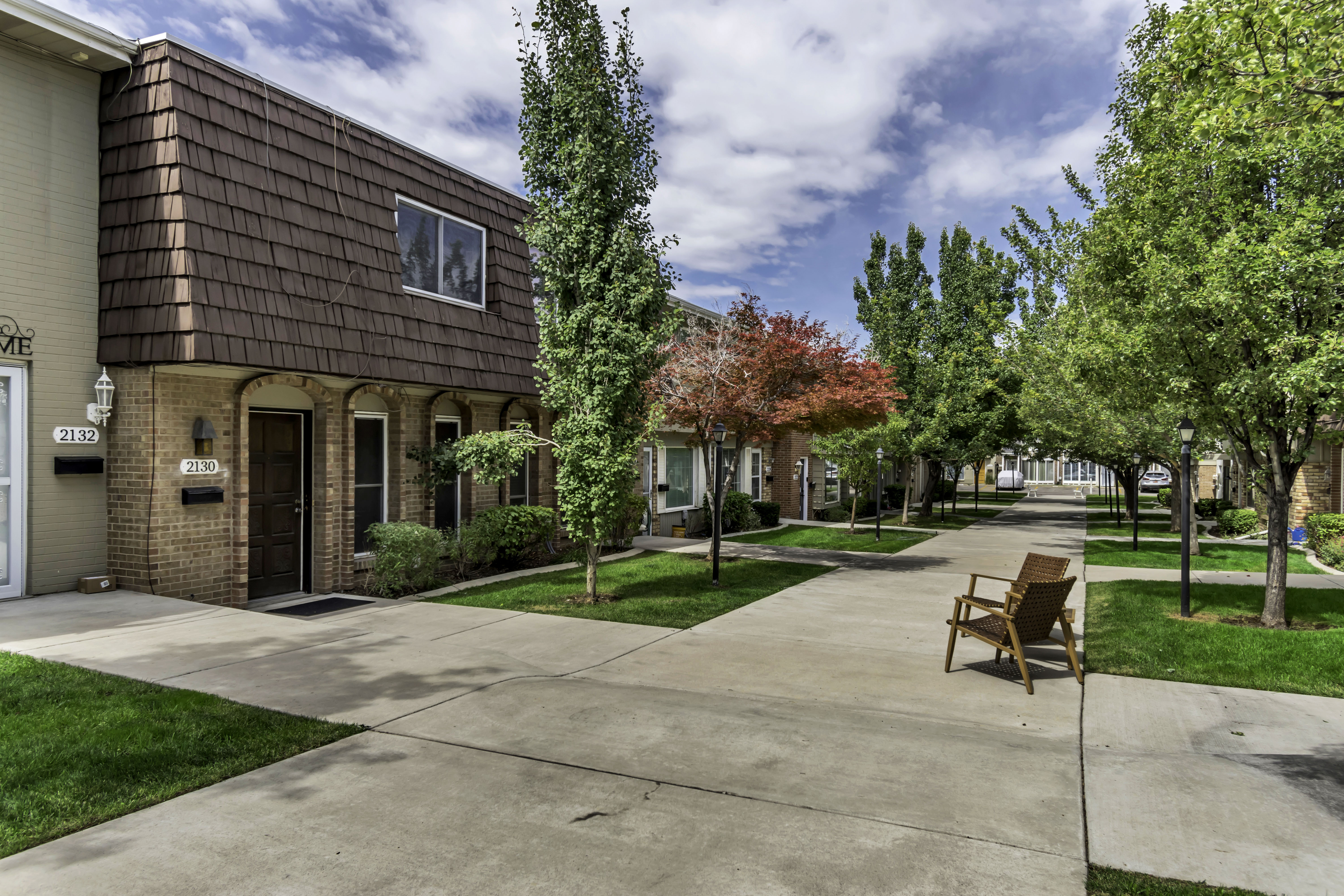 Townhome exterior featuring a brown brick first story and a mansard-style upper level with brown shingles