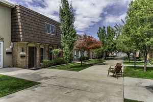Townhome exterior featuring a brown brick first story and a mansard-style upper level with brown shingles
