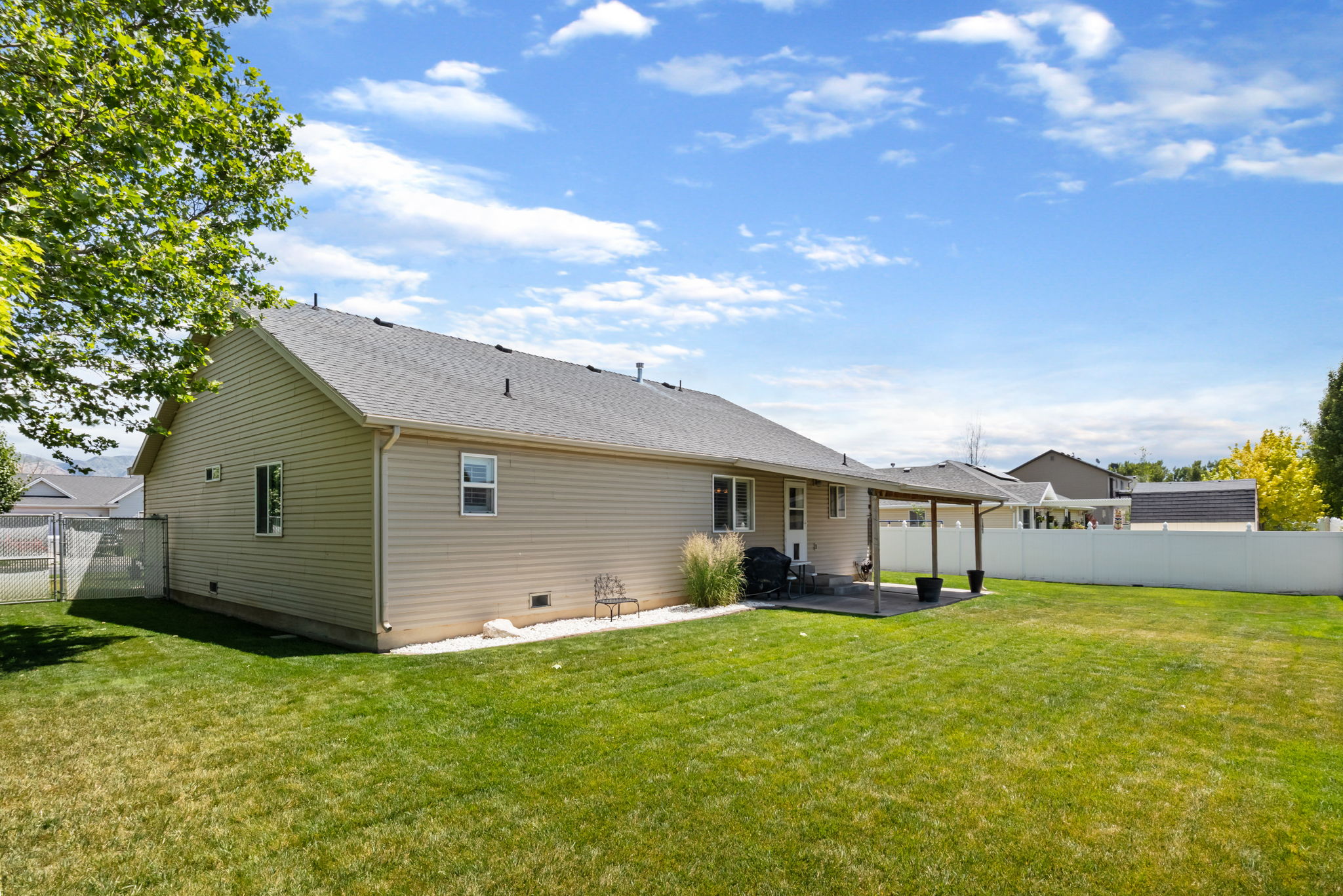 Expansive backyard featuring a large grass area, a covered patio, and a privacy fence