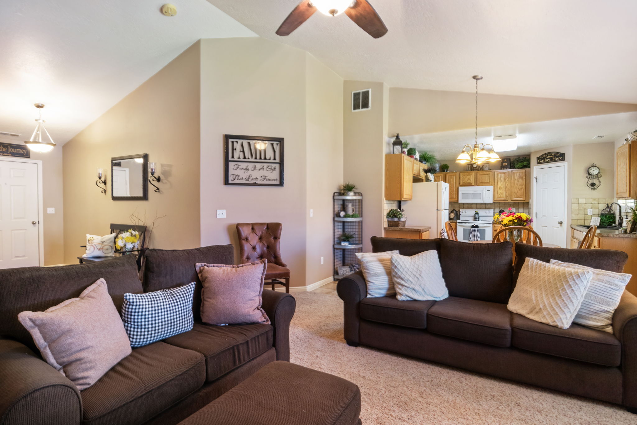 Living area featuring an open concept design with vaulted ceilings, a ceiling fan, and carpet flooring