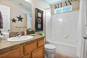 Full guest bathroom featuring a vanity with a countertop, an undermount sink, and wood-finish cabinetry
