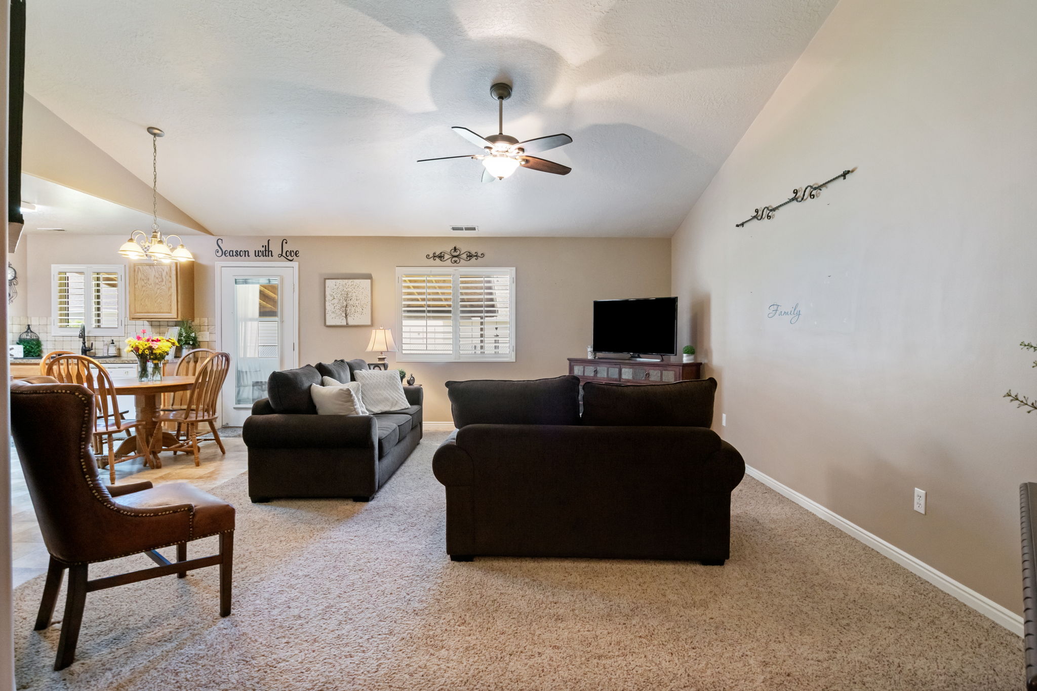 Vaulted ceilings enhance this open-concept living area with neutral carpeting